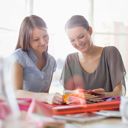 Young businesswomen discussing over fabric swatches in office by level17.